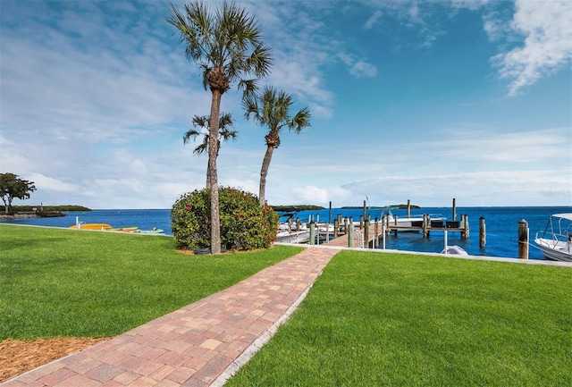 dock area with boat lift, a yard, and a water view