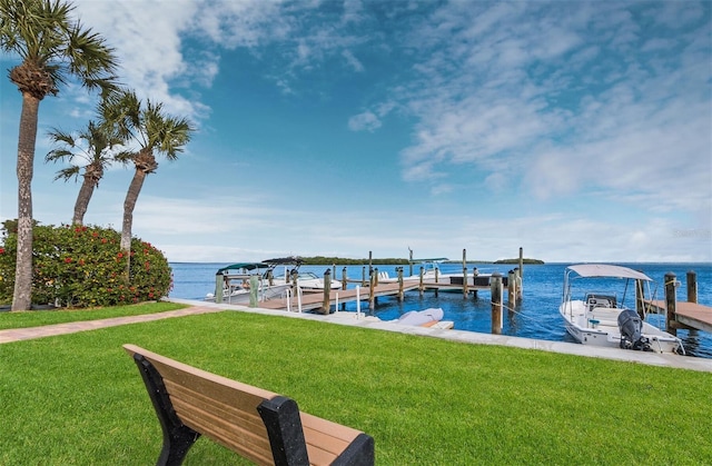 dock area with boat lift, a water view, and a yard