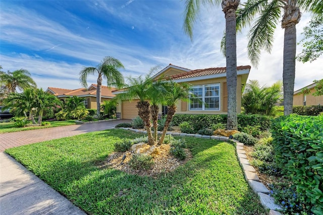 mediterranean / spanish home featuring a front yard and a garage