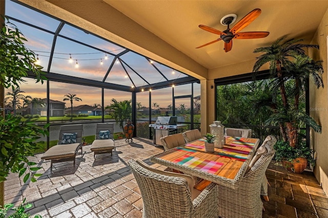 patio terrace at dusk with a lanai, a grill, and ceiling fan