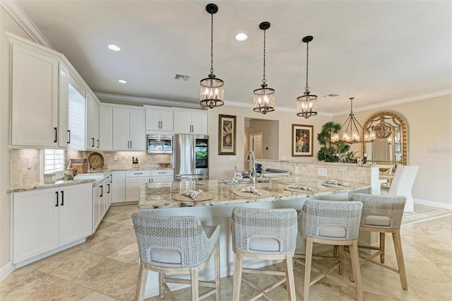 kitchen with appliances with stainless steel finishes, sink, a large island with sink, pendant lighting, and white cabinets