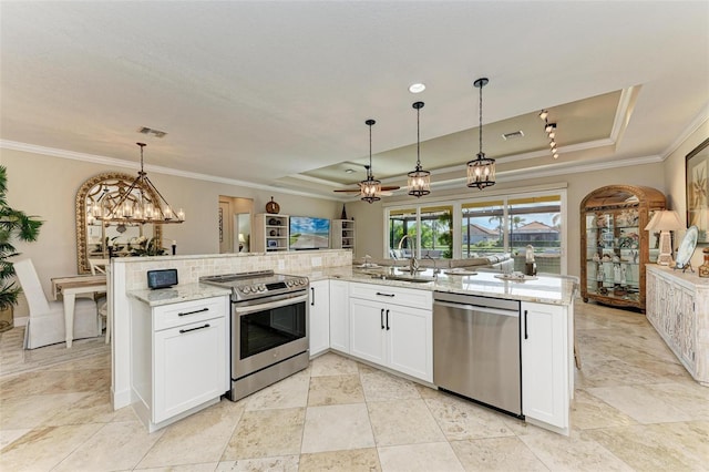 kitchen featuring white cabinets, stainless steel appliances, hanging light fixtures, and a tray ceiling