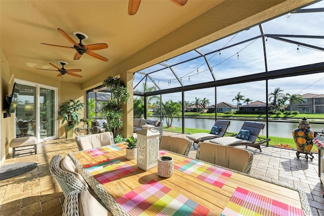 view of patio / terrace with an outdoor living space, a water view, glass enclosure, and ceiling fan