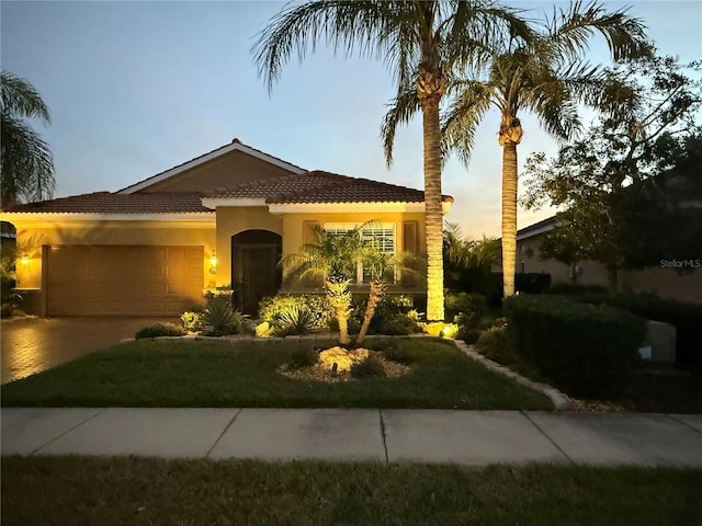 mediterranean / spanish-style home featuring a yard and a garage