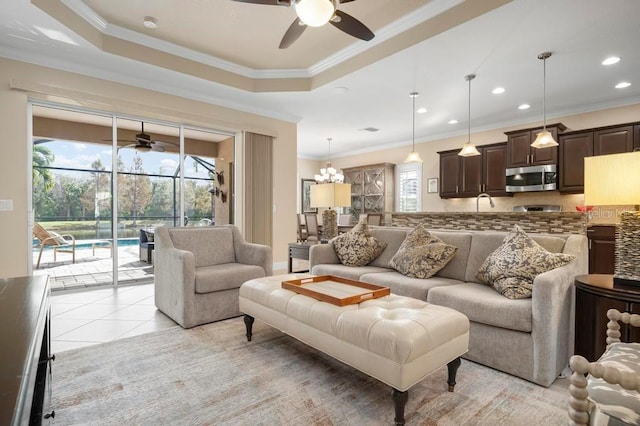 tiled living room featuring a raised ceiling, crown molding, and ceiling fan