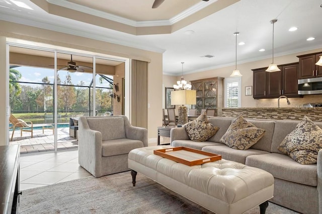 tiled living room with a healthy amount of sunlight, a raised ceiling, and ornamental molding