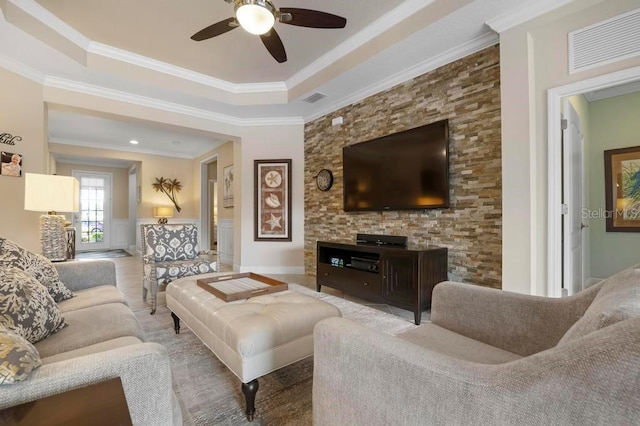 living room with ceiling fan, a raised ceiling, and ornamental molding