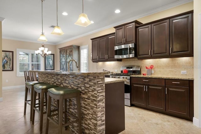 kitchen featuring appliances with stainless steel finishes, decorative light fixtures, and light stone counters