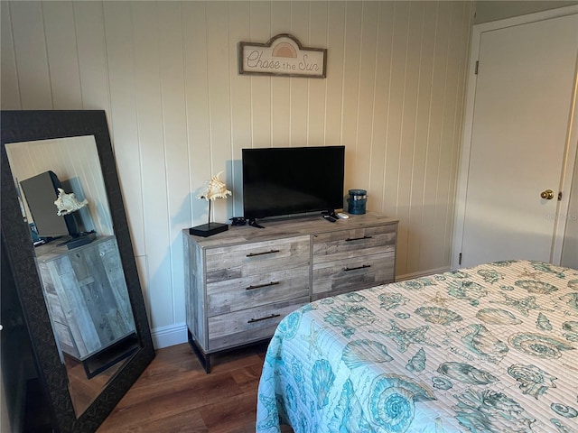 bedroom featuring dark hardwood / wood-style flooring and wood walls