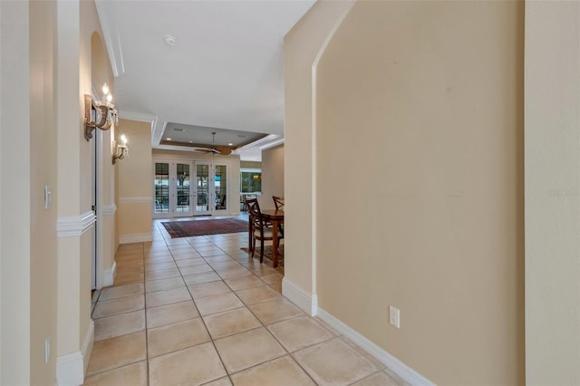 corridor featuring a tray ceiling and light tile patterned floors