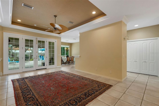 interior space featuring french doors, light tile patterned floors, and a raised ceiling