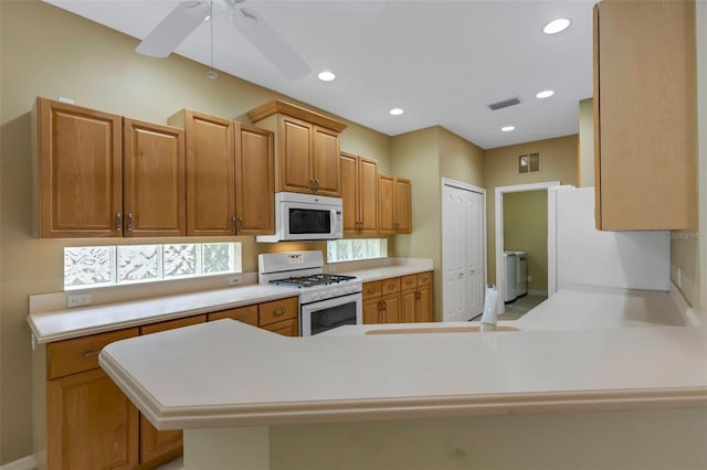 kitchen with ceiling fan, sink, white appliances, and kitchen peninsula