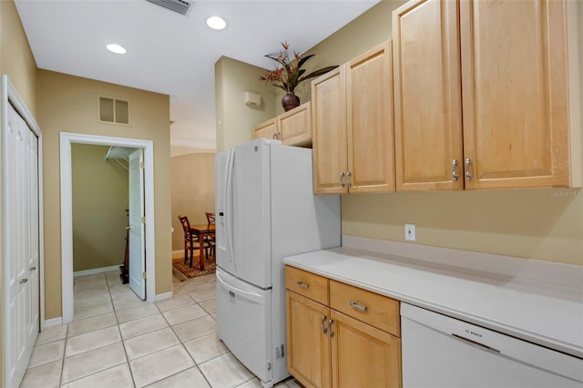 kitchen with light brown cabinets, white appliances, and light tile patterned flooring