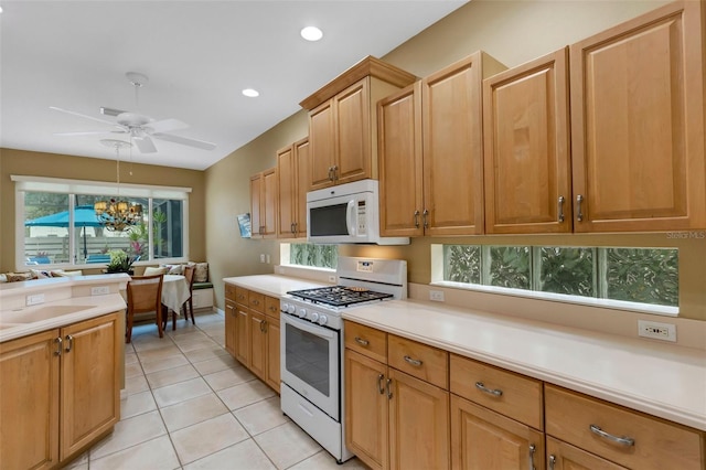 kitchen with ceiling fan with notable chandelier, sink, light tile patterned floors, and white appliances