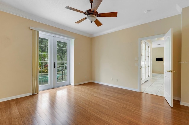 empty room featuring french doors, light wood-type flooring, ceiling fan, and crown molding