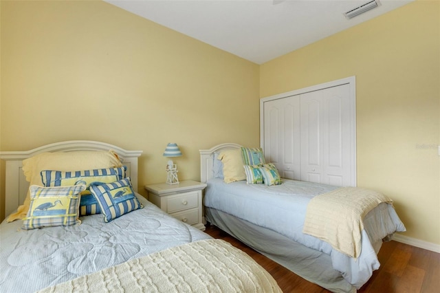 bedroom with dark hardwood / wood-style flooring and a closet