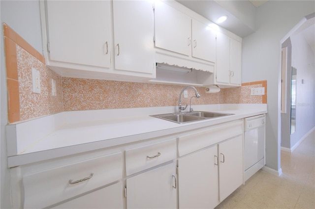 kitchen with white dishwasher, white cabinetry, and a sink