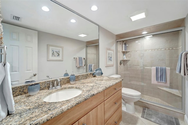 bathroom with tile patterned flooring, vanity, a shower with shower door, and toilet