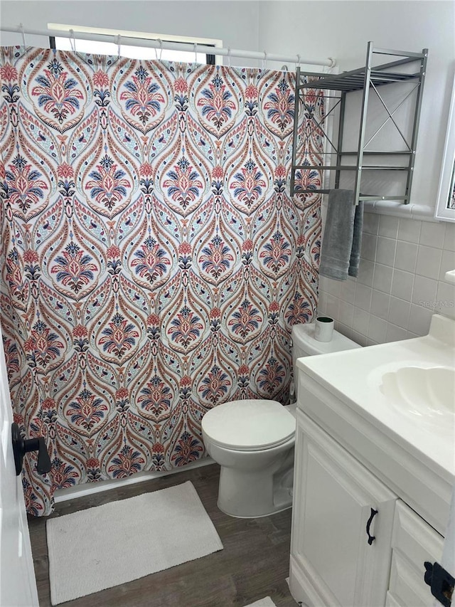 bathroom featuring hardwood / wood-style floors, vanity, decorative backsplash, toilet, and a healthy amount of sunlight