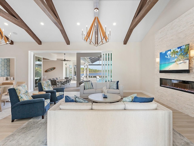 living room with beamed ceiling, a stone fireplace, and light wood-type flooring