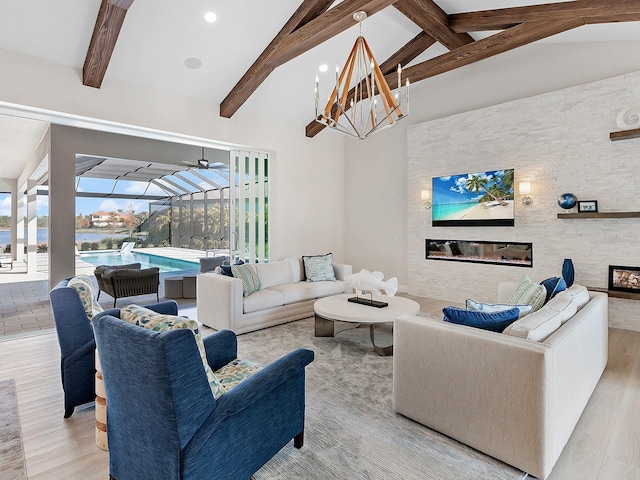 living room with beamed ceiling, light wood-type flooring, a large fireplace, and plenty of natural light