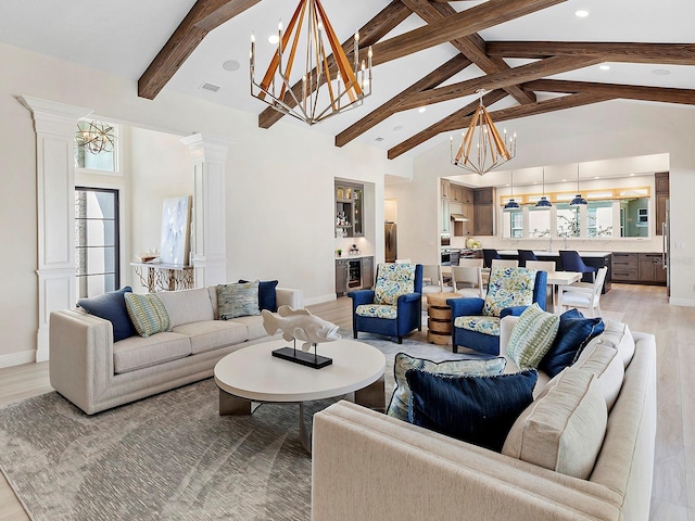 living room with a notable chandelier, beam ceiling, light wood-type flooring, and ornate columns