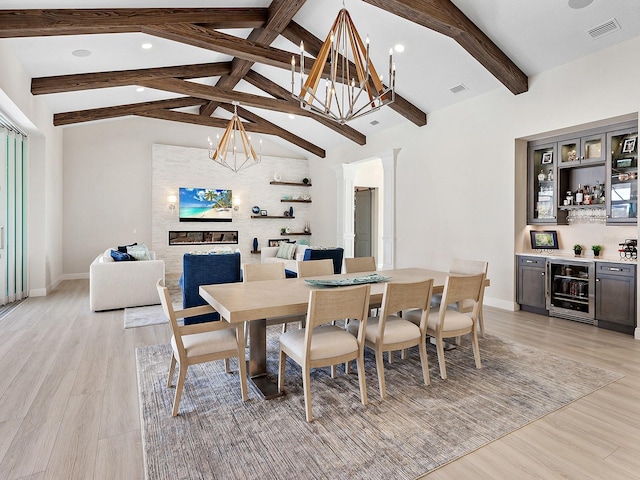 dining space featuring beamed ceiling, beverage cooler, indoor bar, and light wood-type flooring