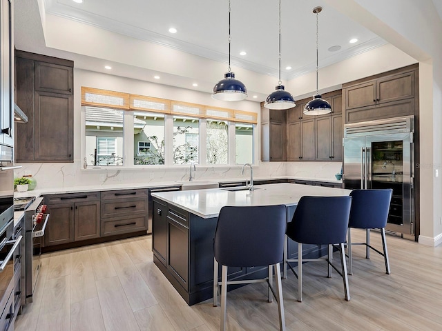 kitchen with a kitchen bar, a wealth of natural light, sink, a center island with sink, and high quality appliances