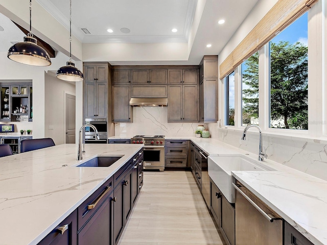 kitchen with dark brown cabinetry, sink, light stone counters, decorative light fixtures, and high end range