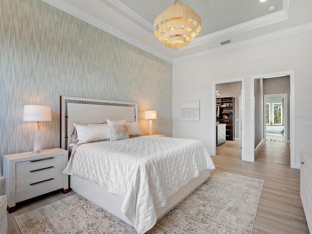 bedroom featuring a spacious closet, crown molding, light hardwood / wood-style flooring, and a notable chandelier