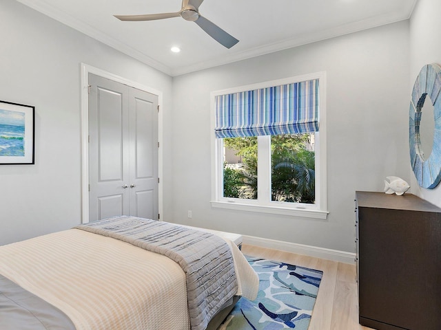 bedroom with ceiling fan, light hardwood / wood-style floors, crown molding, and a closet