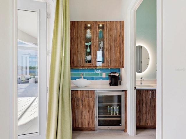 bar featuring tasteful backsplash, sink, and beverage cooler