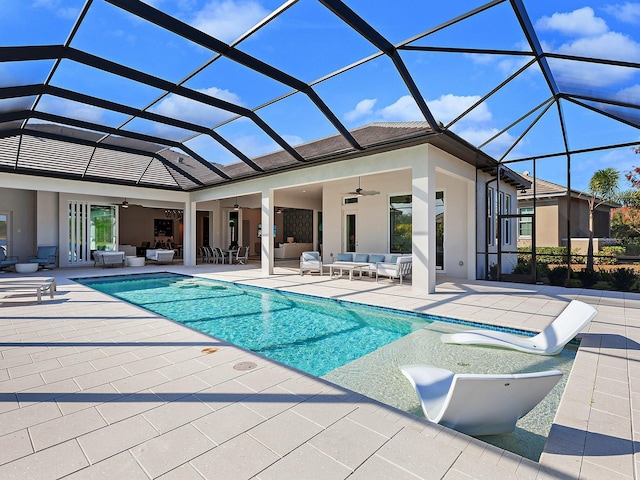 view of pool featuring an outdoor living space, glass enclosure, ceiling fan, and a patio area