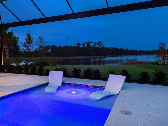 view of swimming pool featuring glass enclosure, a patio area, and a water view