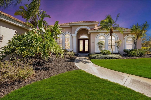 exterior entry at dusk featuring a yard and french doors