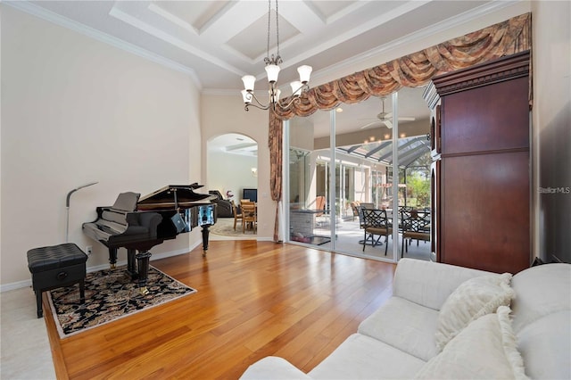 living room featuring wood-type flooring, ceiling fan with notable chandelier, coffered ceiling, and ornamental molding