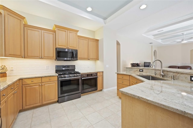 kitchen featuring tasteful backsplash, a raised ceiling, sink, stainless steel appliances, and light stone counters