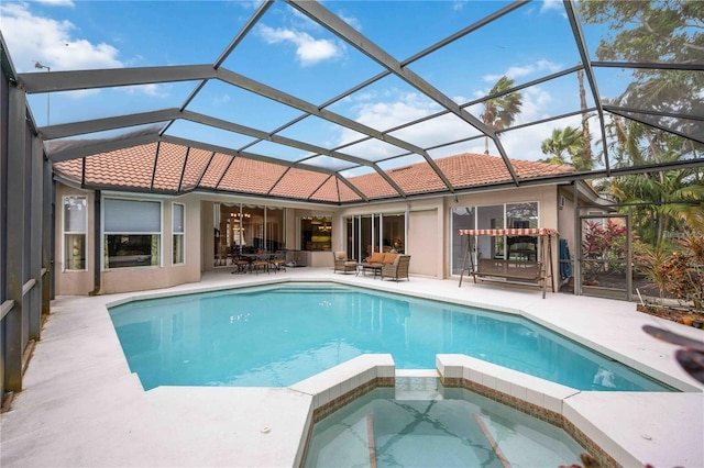 view of swimming pool featuring glass enclosure, an in ground hot tub, and a patio