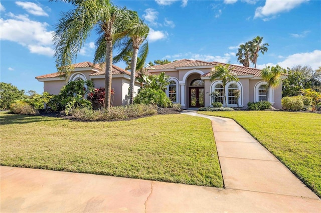 mediterranean / spanish home with a front yard and french doors