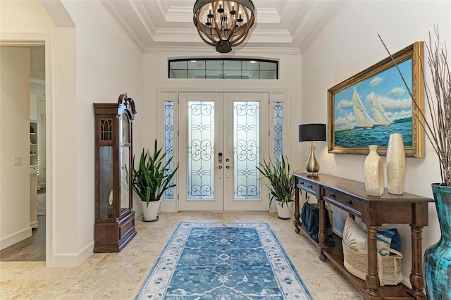 foyer featuring a towering ceiling, french doors, an inviting chandelier, and ornamental molding