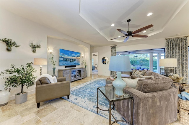 living room with ceiling fan and a raised ceiling