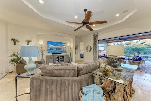 living room with ceiling fan and a tray ceiling