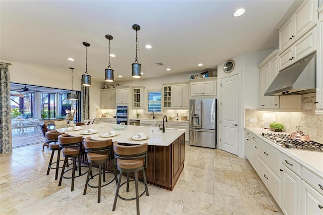 kitchen featuring appliances with stainless steel finishes, a kitchen breakfast bar, backsplash, a spacious island, and pendant lighting