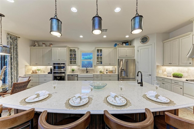 kitchen featuring pendant lighting, backsplash, stainless steel appliances, and a spacious island