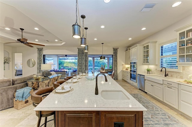 kitchen with a breakfast bar, light stone countertops, hanging light fixtures, and a large island