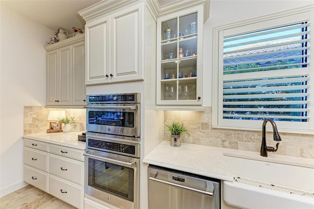 kitchen with decorative backsplash, sink, light stone counters, and appliances with stainless steel finishes