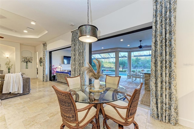 dining space with ceiling fan and a tray ceiling