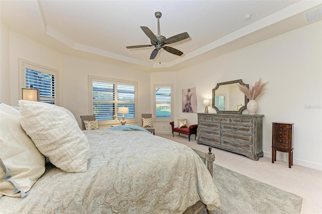 carpeted bedroom featuring ceiling fan and a tray ceiling