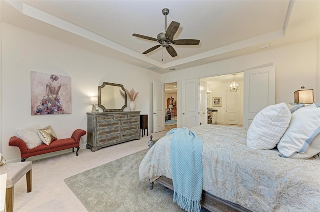 bedroom featuring carpet, ceiling fan with notable chandelier, and a raised ceiling