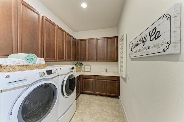 clothes washing area with washer and clothes dryer, cabinets, and sink